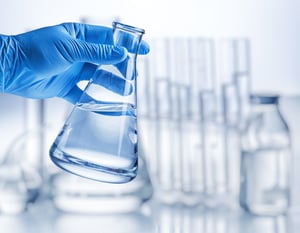 web_Laboratory beaker in analysts hand in plastic glove